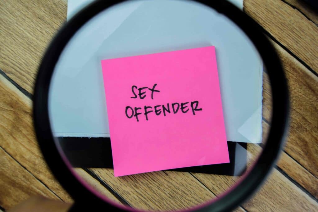 Magnifying glass focusing on note labeled sex offender, symbolizing criminal record or sex crime investigation. Magnifying glass focusing on note labeled sex offender, symbolizing criminal record or sex crime investigation.