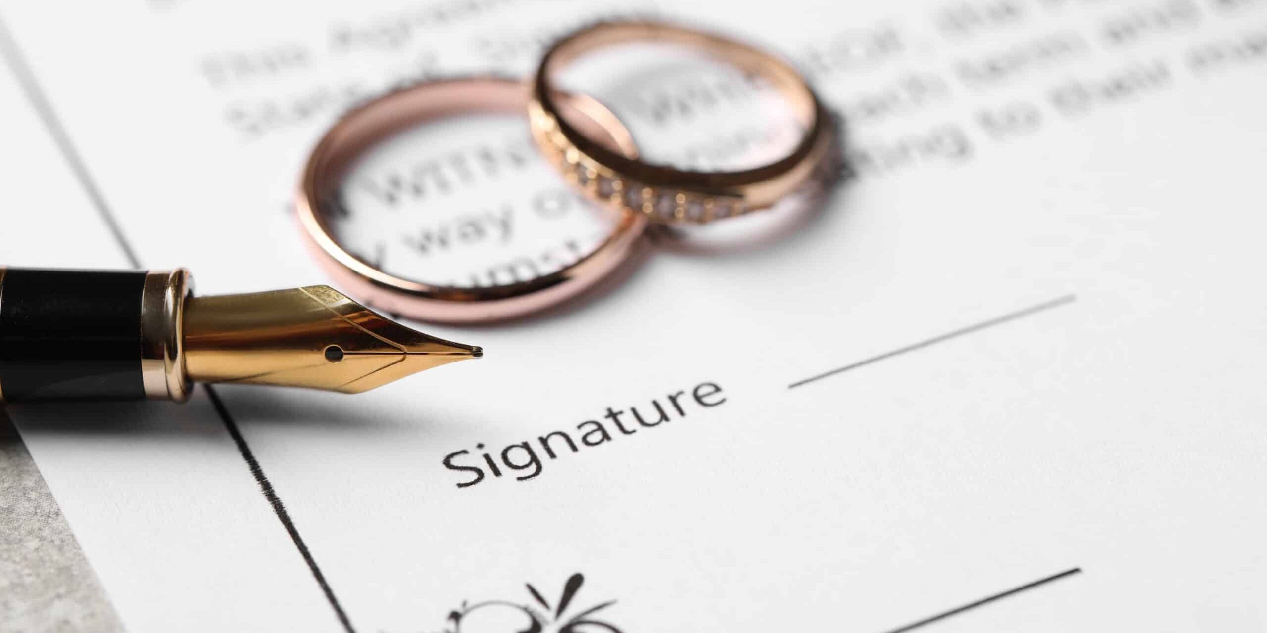 Wedding rings and fountain pen on divorce agreement document ready for signature. Wedding rings and fountain pen on divorce agreement document ready for signature.