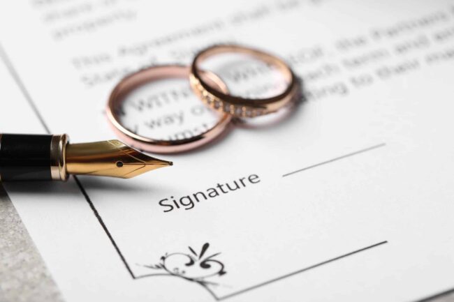 Wedding rings and fountain pen on divorce agreement document ready for signature. Wedding rings and fountain pen on divorce agreement document ready for signature.