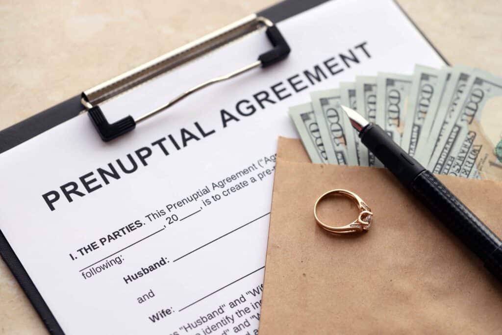 Prenuptial agreement document with engagement ring, money, and fountain pen symbolizing marriage contract and financial planning.